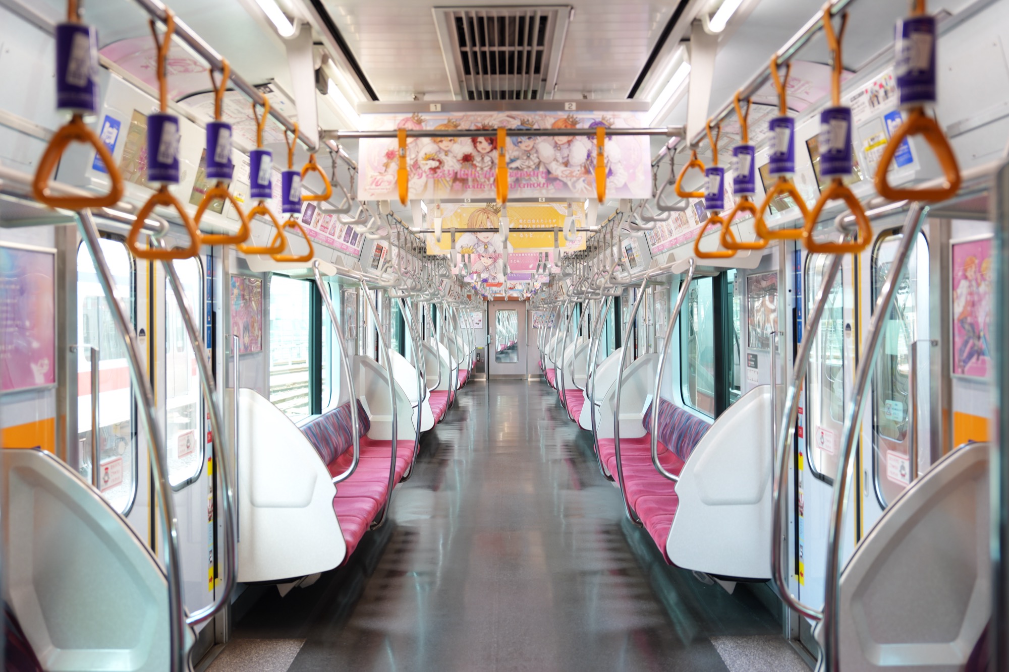 東急東横線の車内全景 - オレンジ色のつり手とピンク色のシートが見える